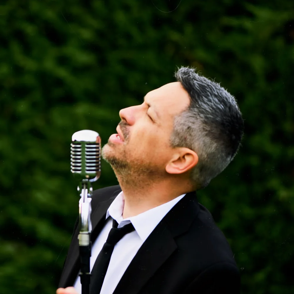 Armando Cacciato canta davanti a un microfono vintage.