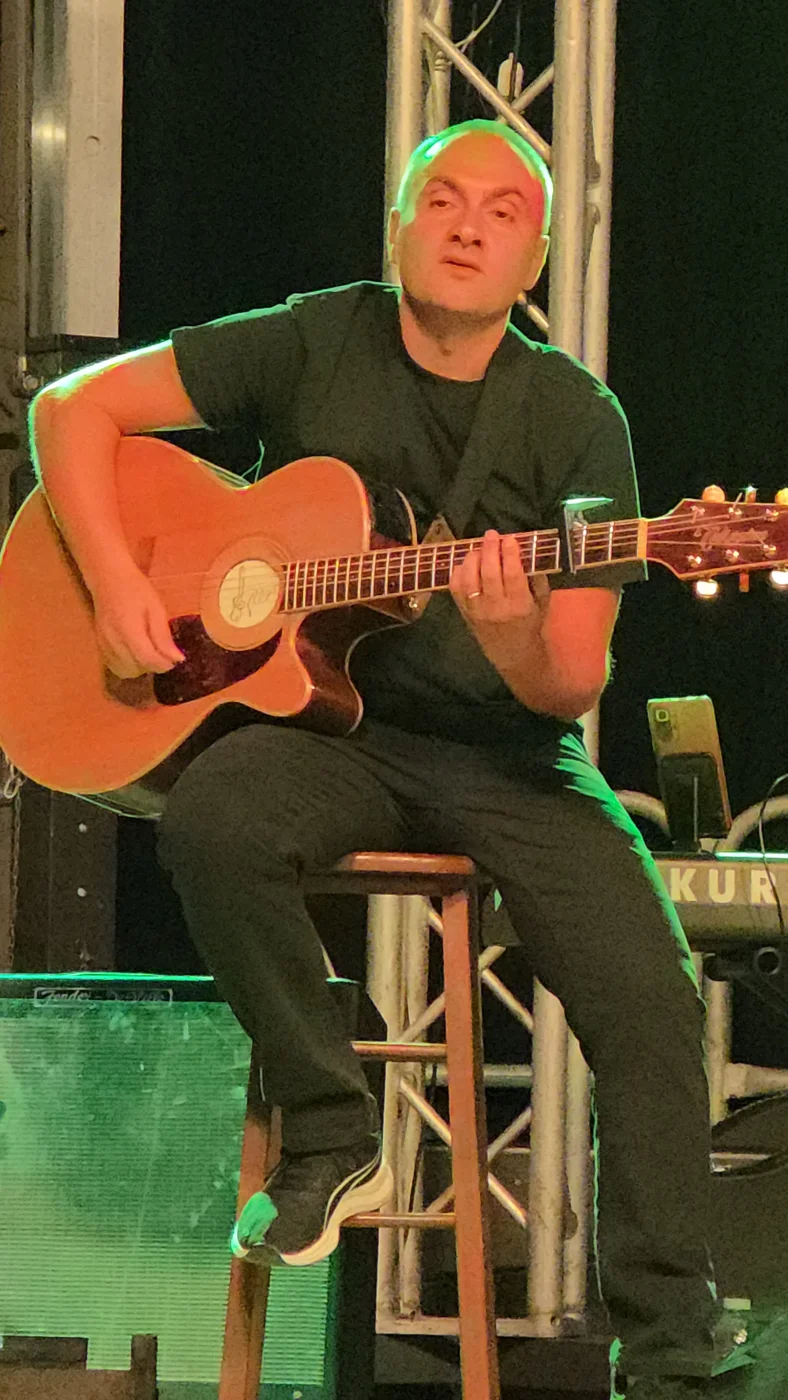 Roberto Puccio suona la chitarra acustica sul palco.
